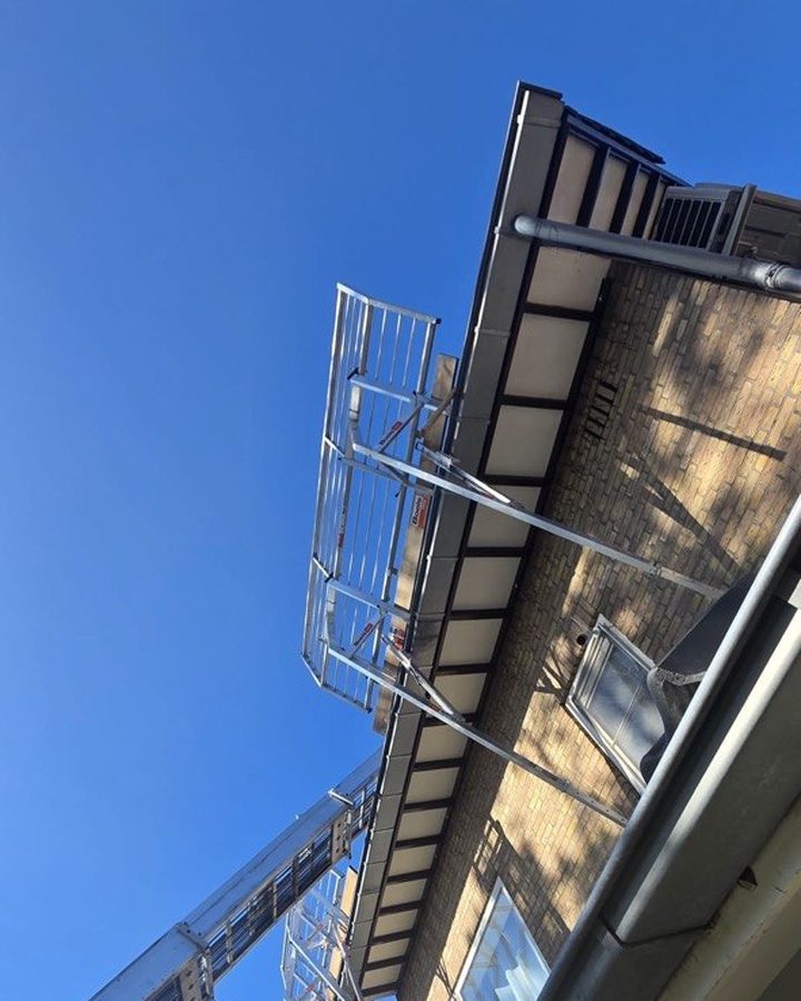 Randbeveiliging langs de dakrand en ladderlift tegen de gevel, opgebouwd voor het isoleren van het pannendak