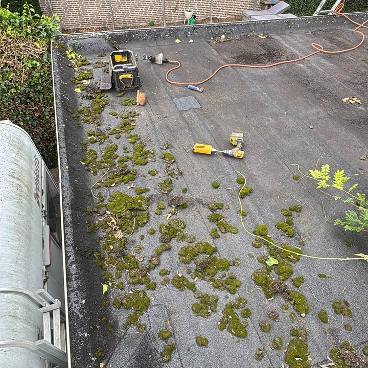 Plat dak met mos en de dichtgezette insnijding van een nulmeting, met het gereedschap van onze vakman ernaast